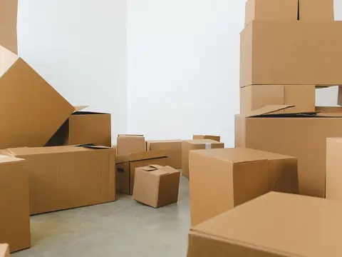 Plain cardboard boxes of different sizes on a concrete floor against a white wall