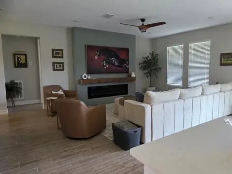 A living room with a cream sectional sofa, two leather armchairs and a wall fireplace