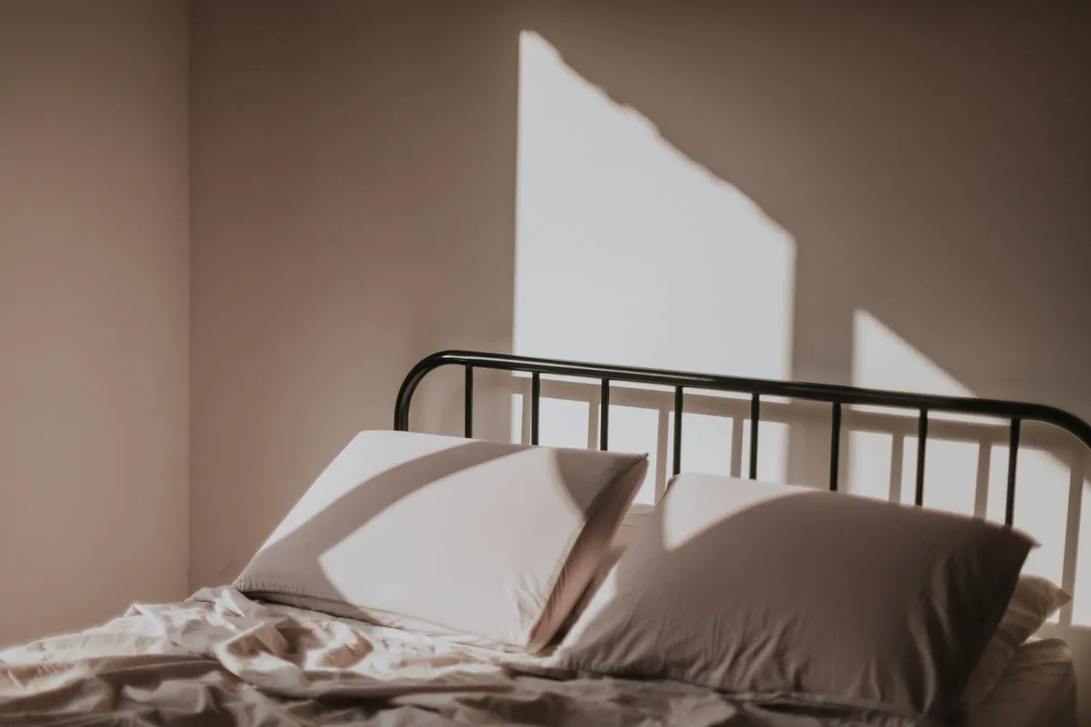Soft morning light highlights a neatly made bed, symbolizing the comfort of a clean home before hiring a maid service.